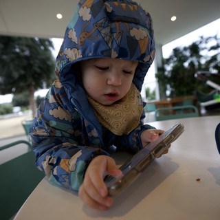 Young Child Using Smartphone at Outdoor Cafe