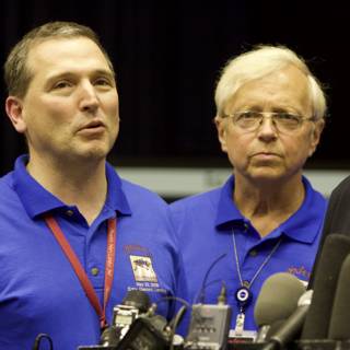 Three Men in Blue Shirts Answer Press Questions