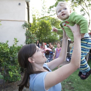 Joyful Mother Lifts Baby High in Backyard