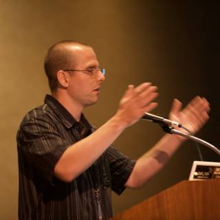 Conference speaker presenting with microphone and laptop