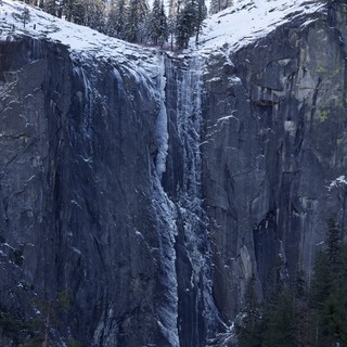Frozen Waterfall Cascading Through Snow-Covered Granite Cliffs