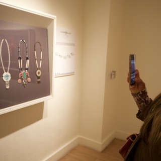 Visitor Photographing Native American Jewelry Display in Museum