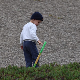 Young Boy Playing With Toy Bat on Sandy Shore