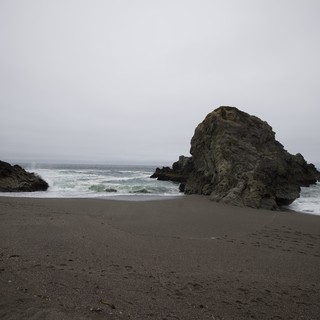 Moody Sea Stack on a Desolate Fog-Shrouded Beach