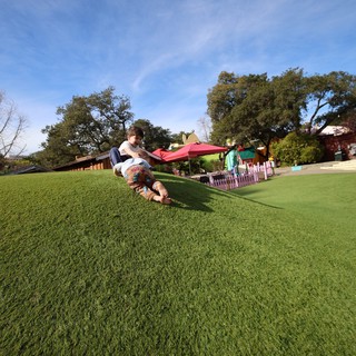 Child Sliding Down Grassy Hill at Colorful Play Area