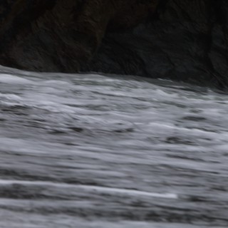 Churning Ocean Waves Against Dark Rocky Cliffs
