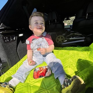 Young Boy Enjoying Picnic in SUV Trunk