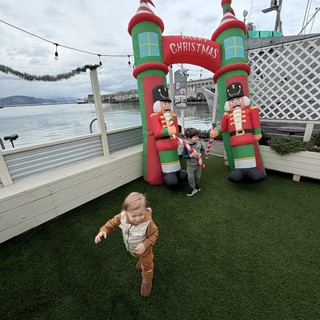 Children Playing Near Inflatable Christmas Decorations by the Water
