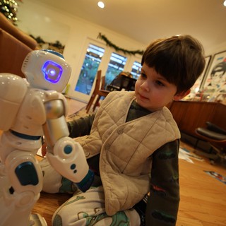 Child Interacting with White Humanoid Robot at Home