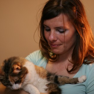 Woman Tenderly Holds Calico Cat in Warm Light