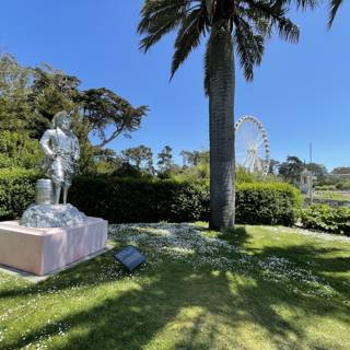 Statue in a Park with Palm Trees and Ferris Wheel