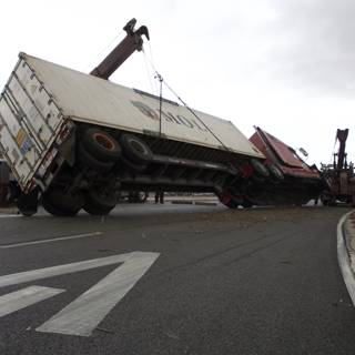 A Crane Lifts an Overturned Truck on Tarmac