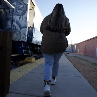 Woman Walking Toward Train at Platform Dusk