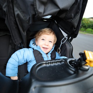 Happy Toddler in Blue Jacket on Stroller Walk