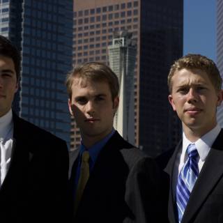 Three Men Pose in Front of a City Building