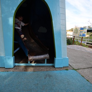 Child Playing in Blue Tunnel Slide at Playground