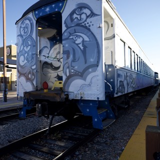 Artistic Train Car with Blue Swirl Murals at Station