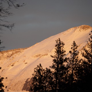 Golden Alpenglow on Snow-Covered Mountain Peak at Dusk