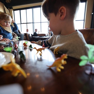 Children Playing with Dinosaur Toys at Restaurant Table