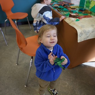 Young Child Playing with Green Toy in Classroom Setting