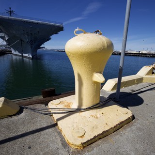 Yellow Mooring Bollard at Naval Harbor with Aircraft Carrier