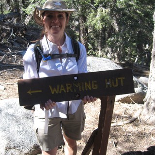 Hiker Poses at Warming Hut Trail Sign
