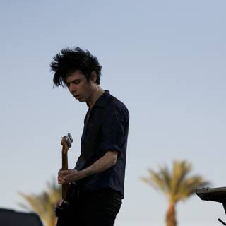 Nick Zinner performs on stage under the blue sky