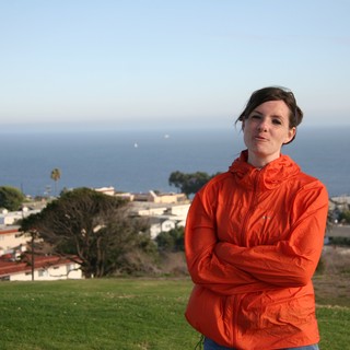 Woman in Orange Jacket Overlooking Coastal Town