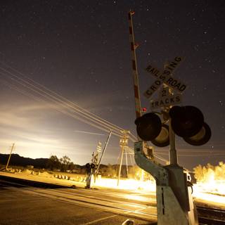 Nighttime Railroad Crossing under a Starry Sky