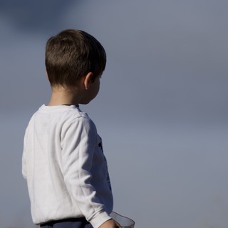 Young Boy Gazes Toward Stormy Mountain Skies