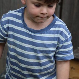 Young Child in Striped Shirt Looking Down Outdoors