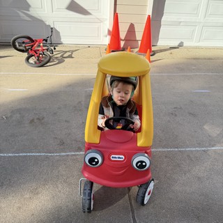 Toddler in Little Tikes Cozy Coupe with Traffic Cone Decoration