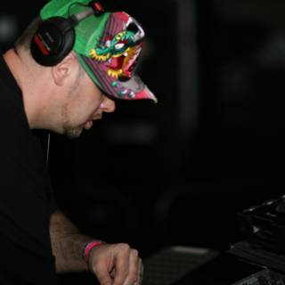 DJ in Action Caption: A male entertainer wearing a baseball cap, headphones, and a fingerless glove, while working with his turntable during a musical performance in 2006.