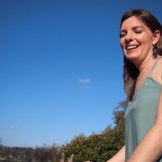Joyful Woman Laughing Under Clear Blue Sky