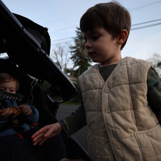 Young Boy Exploring Car Trunk on Suburban Street