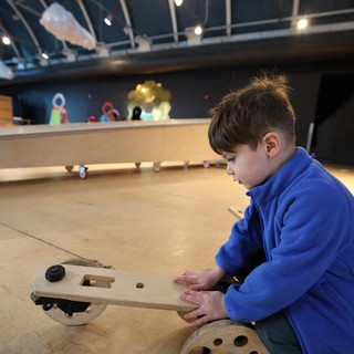Young Inventor Building Wooden Vehicle at Science Center