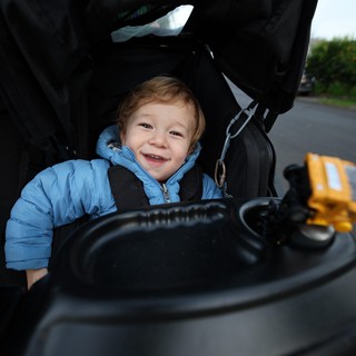 Joyful Toddler in Blue Jacket Sitting in Stroller