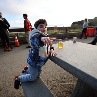 Young Boy Playing on Concrete Bench at Coastal Park