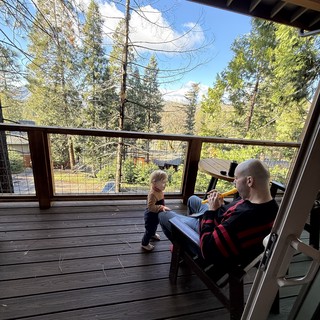 Father Plays Flute for Curious Toddler on Forest Deck