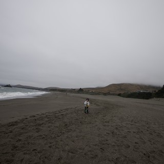 Small Child Standing Alone on Vast Foggy Beach
