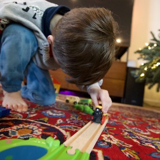 Child Playing with Wooden Train Set at Christmas