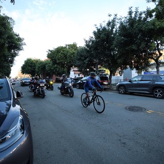 Urban Cyclist Shares Street with Motorcycles at Dusk