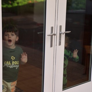 Young Boy Locked Outside Behind Glass Door