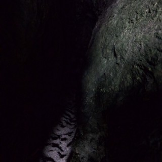 Dark Cave Passage with Sandy Floor and Rocky Wall