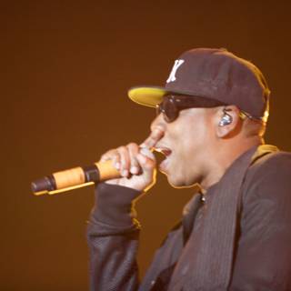 Jay-Z rocks the Coachella stage with signature baseball cap Caption: Jay-Z electrifies the audience at Empire Polo Club sporting his trademark baseball cap while wielding a microphone and captivating the crowd.
