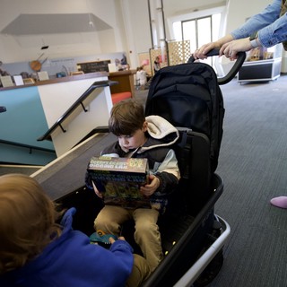 Young Reader in Adaptive Stroller at Community Center