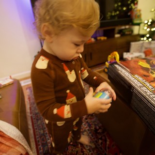 Toddler Opening Christmas Presents by Lit Tree