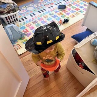 Toddler Playing Firefighter at Home with Toy Helmet