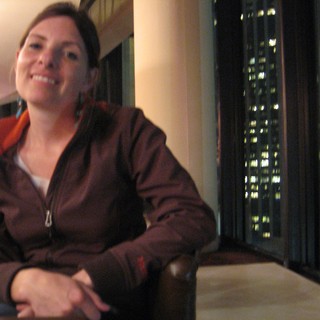 Smiling Woman at High-Rise Bar with City Lights