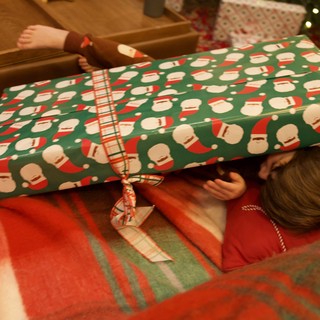 Child Opening Christmas Present with Santa Wrapping Paper